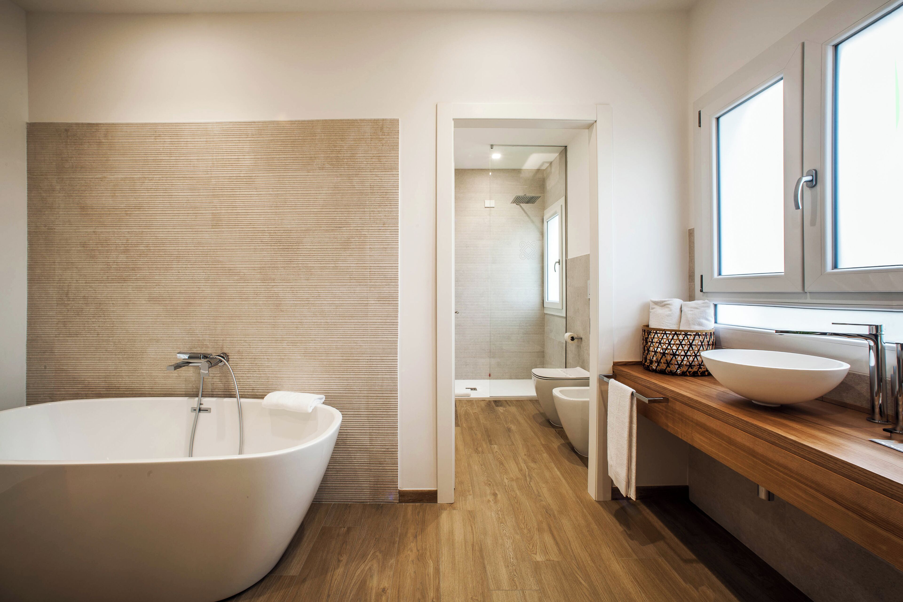 A modern bathroom with a freestanding bathtub, a wooden vanity, and a large mirror above the sink.