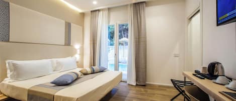 Moderni hotellihuone, jossa on sänky, työpöytä ja televisio.