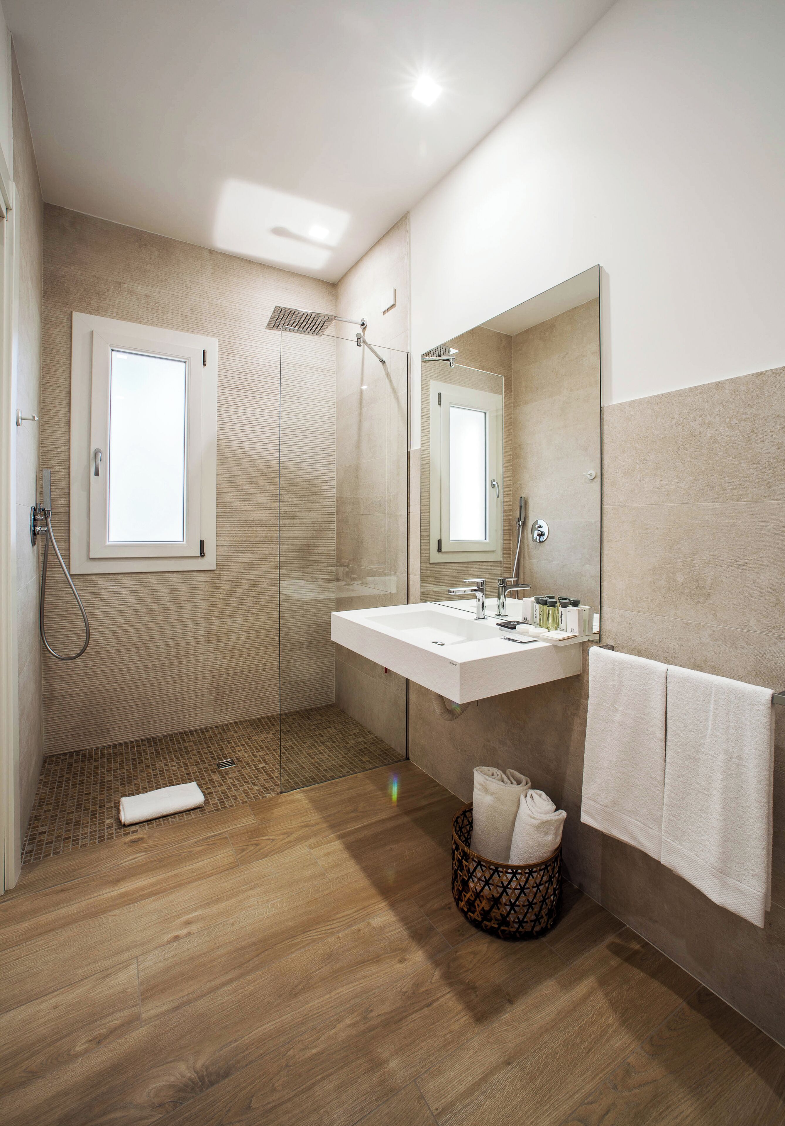 Un baño moderno con ducha, lavamanos, espejo y toallero.