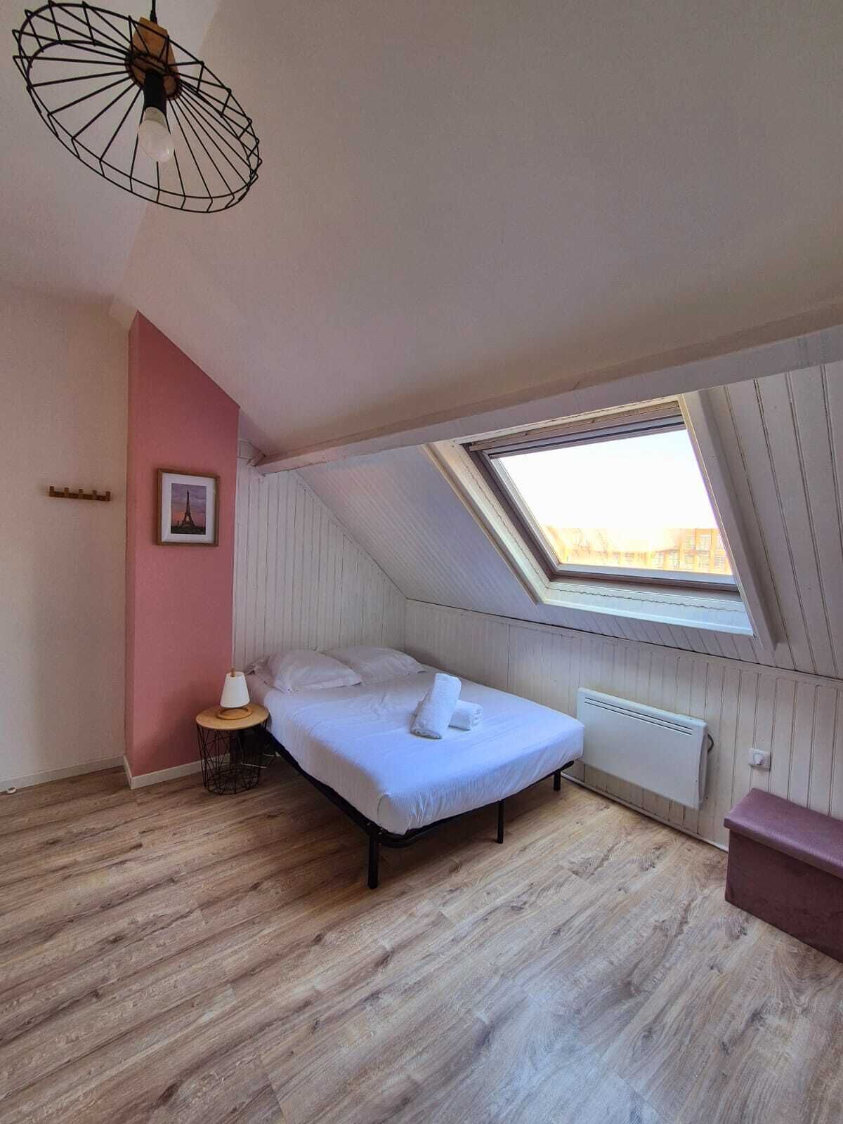 Ett sovrum med ett sluttande tak, ett takfönster, en säng, ett sängbord och ett element.