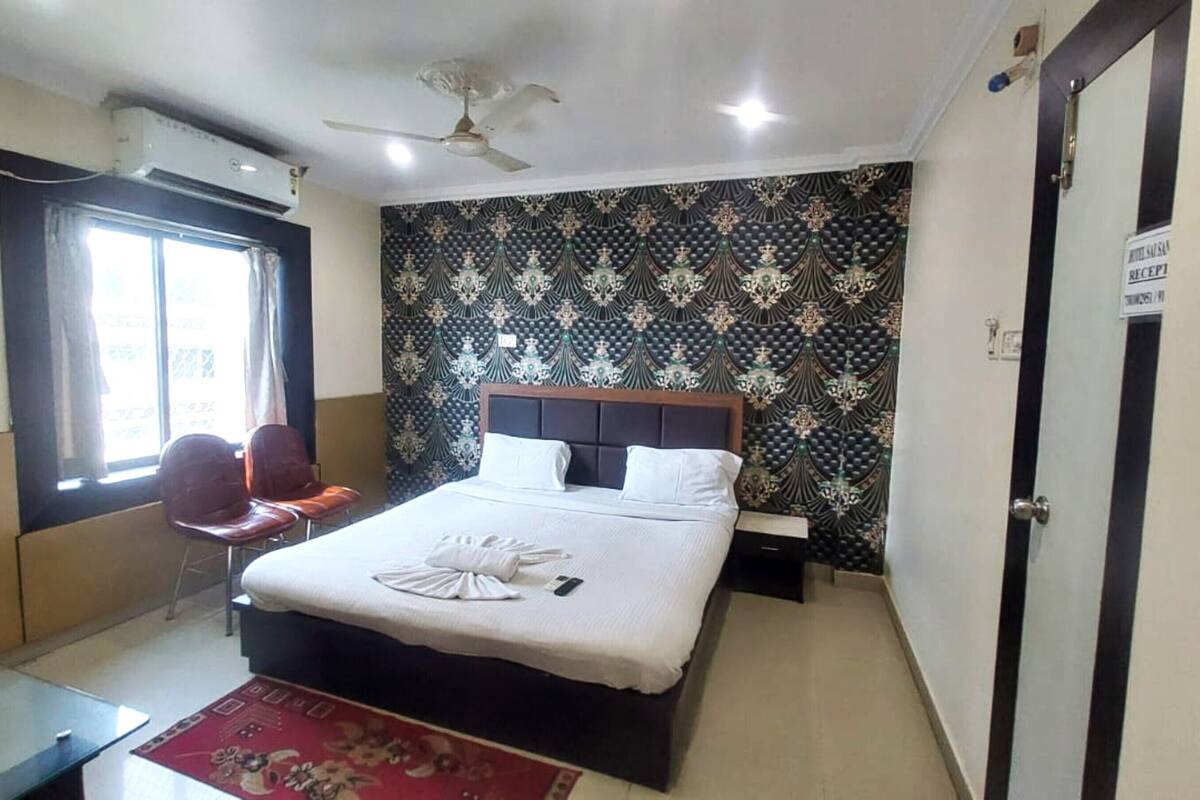 Een hotelkamer met een bed, een bureau, een stoel, een raam en een deur.
