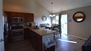 A modern kitchen with stainless steel appliances, a granite countertop, and a dining area with a table and chairs. - Large Home in Aurora with Reservoir View (Aurora)