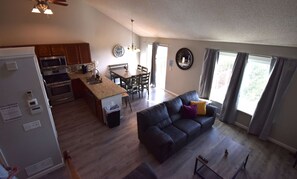 Una cucina moderna con piani in granito, una zona pranzo con tavolo e sedie, un divano in pelle nera e un'ampia finestra con tende.