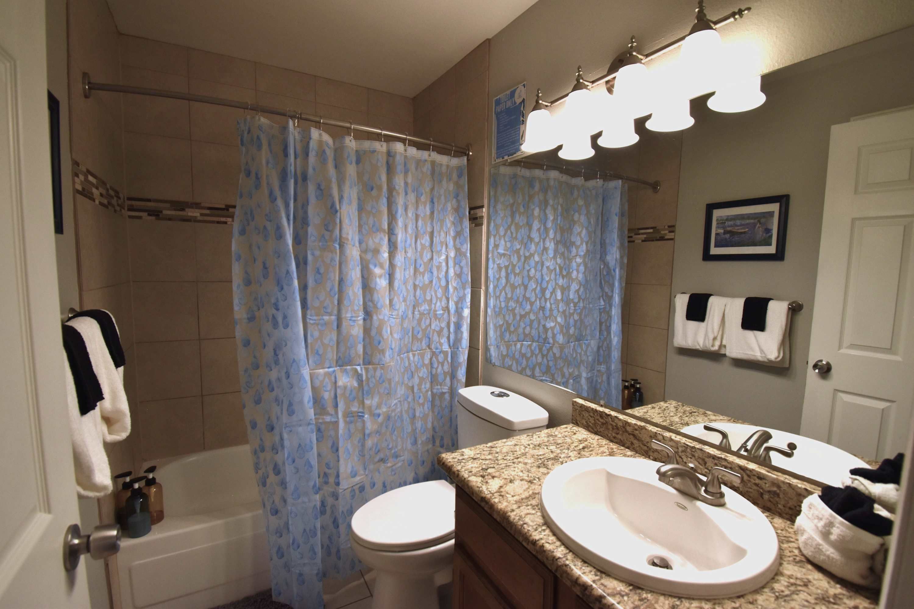 A bathroom with a shower, toilet, sink, and a towel rack.