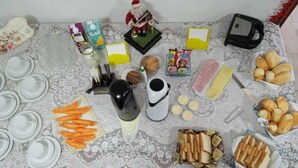 A table with various food items and kitchenware, including plates, a coffee maker, and a Santa figurine. - Acalanto praia  (Peruibe)