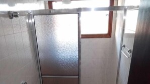 A small, tiled bathroom with a toilet, bidet, and a shower area. - Acalanto praia  (Peruibe)