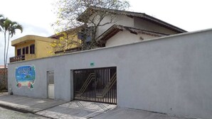 A building with a gated entrance, a mural on the wall, and a number '550' sign. - Acalanto praia  (Peruibe)