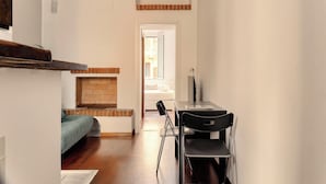 A narrow hallway with a bed on the left, a fireplace, and a table with chairs in the center. - JOIVY Cosy flat access to city centre (Milan)