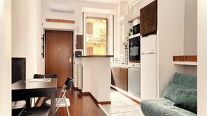 A compact kitchen with a dining area, a sofa, and a view of the outside. - JOIVY Cosy flat access to city centre (Milan)
