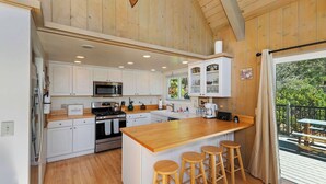 Una cocina amplia con armarios de madera, una isla central con taburetes y vistas al exterior.
