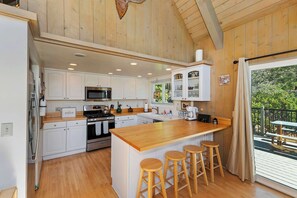 A spacious kitchen with wooden cabinets, a central island with stools, and a view of the outdoors.