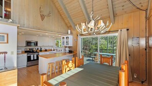 Una cocina amplia con electrodomésticos modernos, una zona de comedor con mobiliario de madera y un gran ventanal con vistas al exterior.