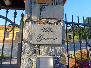 A stone wall with a sign that reads "Villa Guanna" and a metal gate. - JOIVY Villa Guanna Charming Flat Garden (Castiglione Chiavarese)