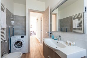 Ein modernes Badezimmer mit Waschmaschine, Waschbecken und großem Spiegel.