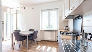 Una cocina moderna con comedor, que incluye una estufa, cafetera y una ventana con cortinas.