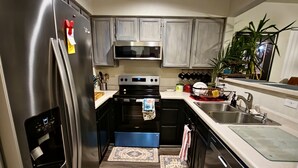A modern kitchen with stainless steel appliances, wooden cabinets, and a central island. - Casa de gato (Westminster)