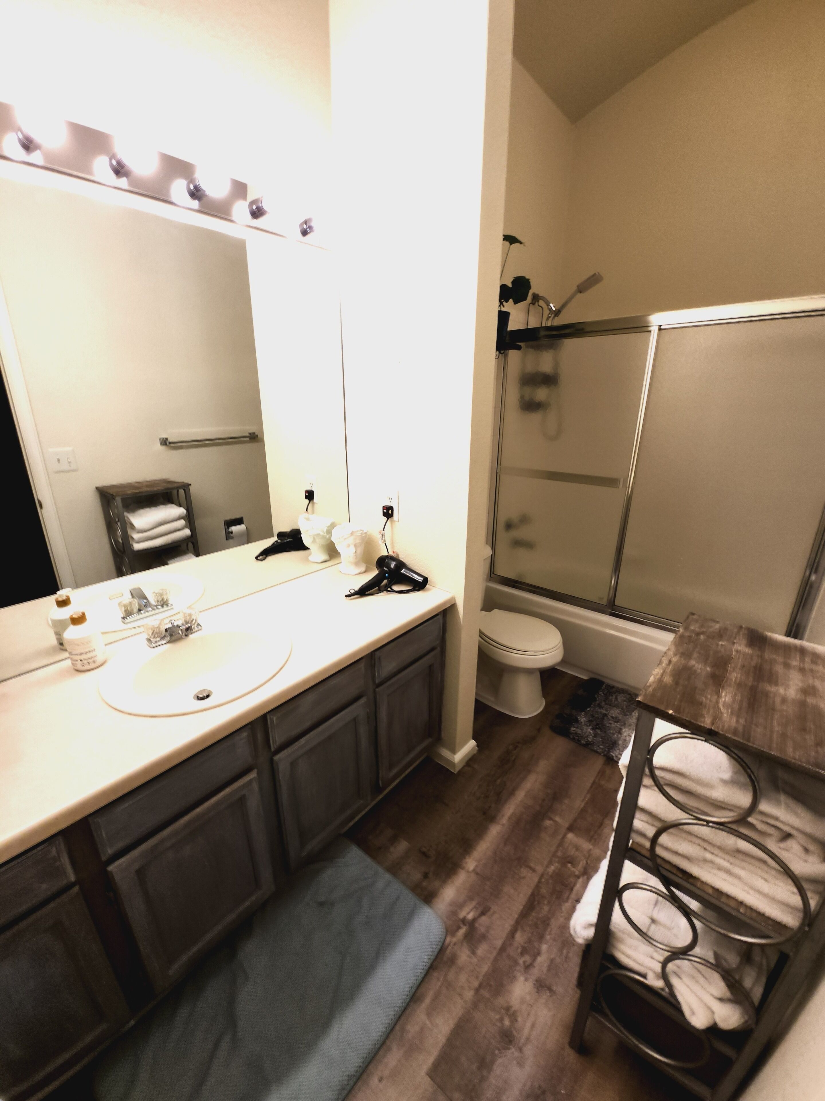 A bathroom with a sink, mirror, towel rack, and shower.