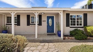 Ein zweistöckiges Haus mit blauer Haustür, der Hausnummer 3430, weißen Außenwänden und schwarzen Fensterläden.