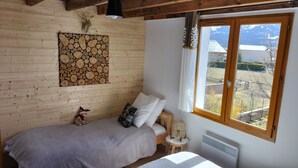 A cozy room with a bed, a decorative wall piece, a window with a view of the outdoors, and a small bedside table. - Semi-detached house, 3* 5 beds, 2 bedrooms garage parking, enclosed garden, WIFI (Bolquère)
