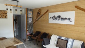 A cozy living room with a wooden wall, a sofa, chairs, a dining table, and a mounted picture of mountains. - Semi-detached house, 3* 5 beds, 2 bedrooms garage parking, enclosed garden, WIFI (Bolquère)