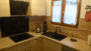 A modern kitchen with a black induction cooktop, a kettle, a coffee maker, and a sink. - Semi-detached house, 3* 5 beds, 2 bedrooms garage parking, enclosed garden, WIFI (Bolquère)