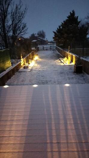 En snötäckt gång som leder fram till en byggnad med upplysta lampor.