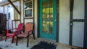 A house with a green door, two red chairs, and a welcome mat outside. - Tiled Shower, Walk to Main, Kitchenette, Smart TV (Fredericksburg)
