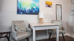 A room with two armchairs, a small table, a large abstract painting, and a mirror on the wall. - Tiled Shower, Walk to Main, Kitchenette, Smart TV (Fredericksburg)