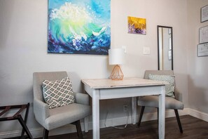Una habitación con dos sillones, una mesita, un cuadro abstracto grande y un espejo en la pared.