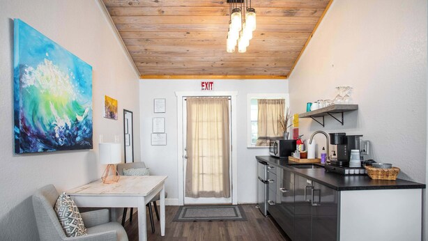 A compact kitchenette with a coffee machine, a sink, and a shelf with glassware. - Tiled Shower, Walk to Main, Kitchenette, Smart TV (Fredericksburg)