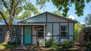 A single-story house with a green door, a front porch, and a small garden.