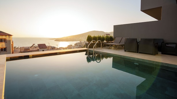 Piscina con vistas al mar y a las montañas, mobiliario exterior y un diseño arquitectónico moderno.