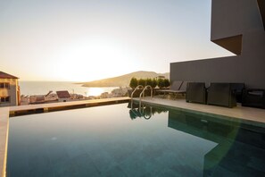 A swimming pool with a view of the sea and mountains, outdoor seating, and a modern architectural design. - Ionian Premium Villas (Sarande)