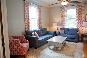 A living room with two sofas, a coffee table, and a patterned armchair. - Chesapeake Charm Estate, Two Blocks from the Beach (Cape Charles)