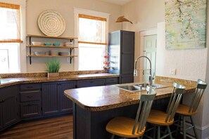 A kitchen with dark cabinets, a granite countertop, a sink, and a bar stool.
