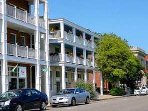 A multi-story building with balconies, a sign for a restaurant, and parked cars. - Chesapeake Charm Estate, Two Blocks from the Beach (Cape Charles)