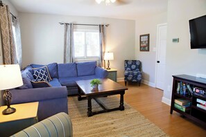 A living room with a sofa, coffee table, armchair, and a bookshelf.