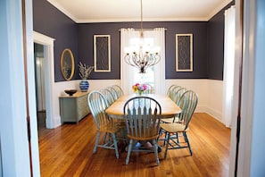 A dining room with a wooden table and six chairs, a chandelier, and decorative wall art. - Chesapeake Charm Estate, Two Blocks from the Beach (Cape Charles)