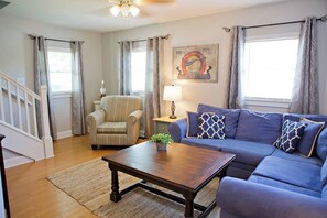 A living room with a blue sofa, striped armchair, wooden coffee table, and a lamp.