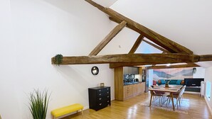 Un ampio loft con soffitti alti, travi in legno a vista, angolo cottura e zona pranzo con tavolo e sedie in legno.
