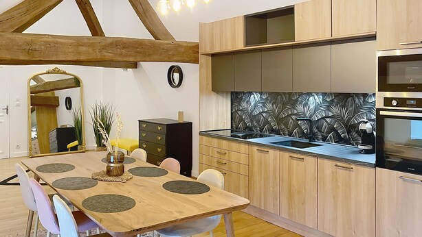 Una cucina moderna con mobili in legno, forno integrato e zona pranzo con tavolo e sedie in legno.