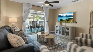 A living room with a sofa, armchairs, a coffee table, a television, and a cabinet.