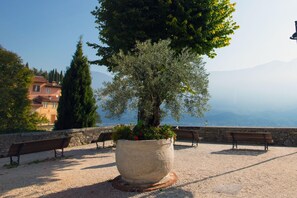 A park with a large tree planter, benches, and a stone wall. - Casa Dei Nonni Tremosine 2 with Lake View Terrace, Tremosine, Italy (Tremosine)