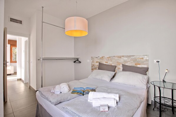 A hotel room with a bed, a bedside table, a lamp, and a view of the outside. - Casa dei Nonni Tremosine 1 with Lake View Terrace, Tremosine, Italy (Tremosine)
