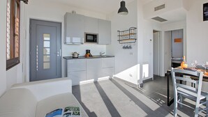 A modern kitchen with white cabinets, a microwave, and a hanging pot rack.