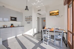 Une cuisine moderne avec des meubles blancs, un four à micro-ondes et un porte-bouteilles à vin suspendu.