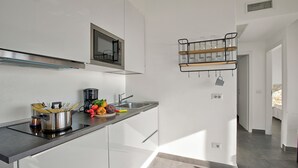 A modern kitchen with a stainless steel range hood, a built-in microwave, and a glass-top island with cooking utensils.