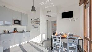 A modern kitchen with white cabinets, a microwave, and a hanging light fixture.