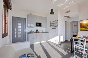 Cozinha moderna com micro-ondas embutido, área de jantar com mesa e cadeiras, e uma janela grande que permite entrada de luz natural.