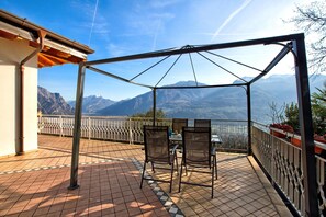 Een terras met een tafel en stoelen, met uitzicht op een bergachtig landschap.